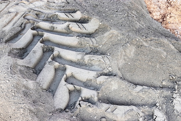 Une Marque De Bande De Roulement D'une Roue D'un Véhicule De Construction Sur Le Sol. Empreinte De Machinerie Lourde. Forme De Roue De Véhicule De Boue Séchée.