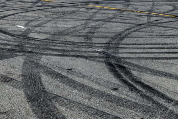 Marque de piste de pneu sur la texture et l'arrière-plan de la piste de course de route goudronnée d'asphalte Résumé fond noir traces de pneus déraper sur la route goudronnée dans le circuit de course Marque de pneu marque de dérapage sur la route goudronnée