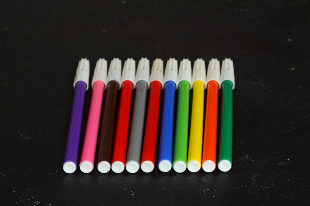 Marqueurs multicolores pour dessiner des marqueurs sur un fond noir isolé