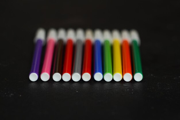 Marqueurs multicolores pour dessiner des marqueurs sur un fond noir isolé
