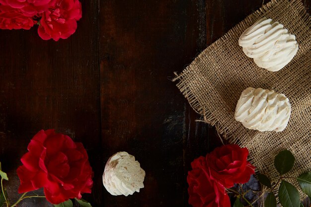 Des marshmallows naturels faits à la main sur des sacs Arrière-plan rustique avec des roses rustiques fraîches Vue supérieure Espace de copie