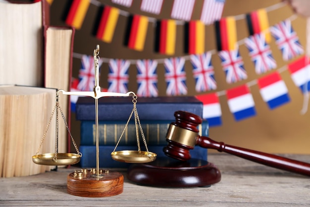 Photo marteau en bois avec livres d'échelles de justice et drapeaux nationaux sur fond marron