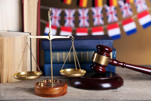 Photo marteau en bois avec des livres de justice et des drapeaux nationaux sur fond brun