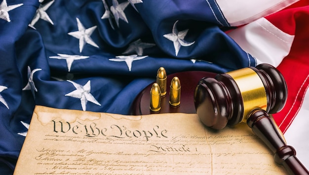 marteau de juge et cartouche de pistolet sur une Constitution américaine avec le drapeau américain américain. idéal pour les mises en page de sites Web et de magazines