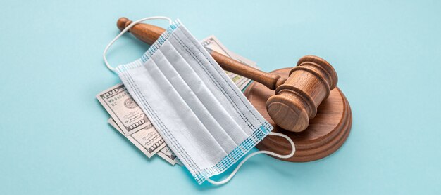Marteau de juge avec masque médical et argent sur fond bleu La corruption dans le concept de domaine médical
