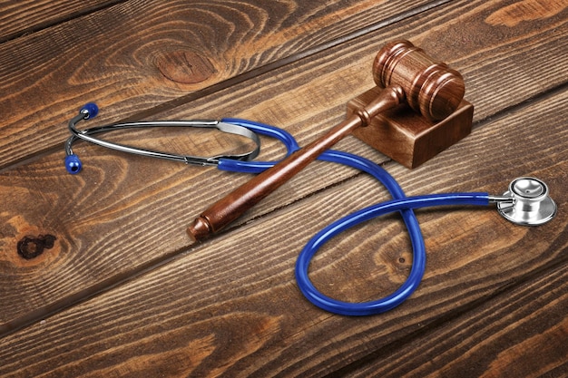 Marteau et stéthoscope sur fond de bois, photo symbole pour maladresse et erreur médicale