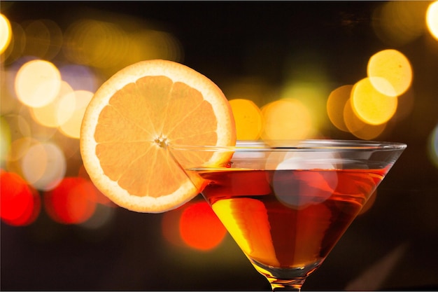 Martini en verre avec tranche d'orange sur fond flou foncé