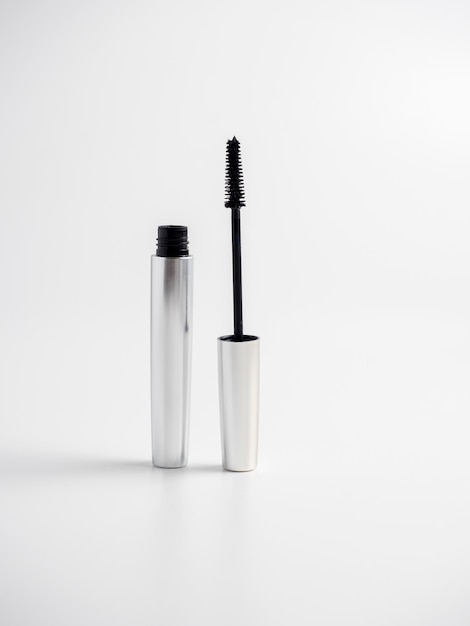 Le mascara dans un tube argenté se dresse sur un fond blanc. Brosse pour appliquer le mascara. Cosmétologie, soins personnels. La beauté des femmes