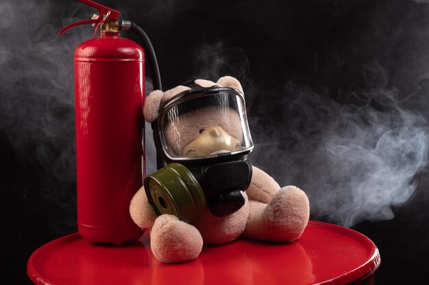 La mascotte des pompiers est un ours en peluche dans un masque à gaz avec un extincteur en fumée sur fond sombre