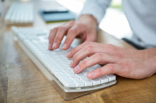 Masculine mains tapant sur le clavier dans un bureau lumineux