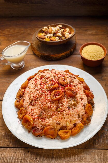 Masfouf de couscous au lait d'amande avec fruits secs et noix sur une table en bois à côté du safran