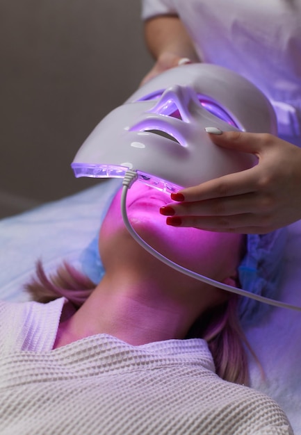 Masque anti-âge à lumière LED pour les soins de la peau du visage dans un spa au ralenti Une femme allongée sur un canapé dans un masque spécial Technologies modernes de beauté et de santé