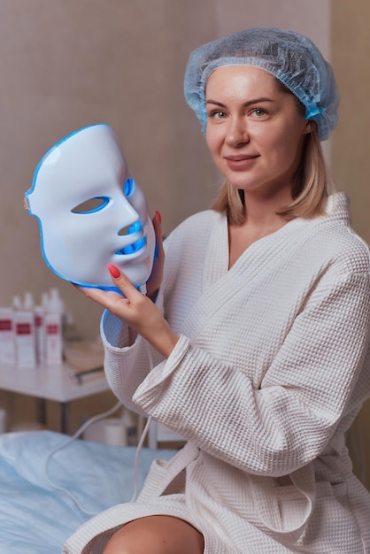 Masque anti-âge à lumière LED pour les soins de la peau du visage dans un spa au ralenti Une femme allongée sur un canapé dans un masque spécial Technologies modernes de beauté et de santé