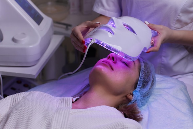 Masque anti-âge à lumière LED pour les soins de la peau du visage dans un spa au ralenti une femme allongée sur un canapé dans une spécification