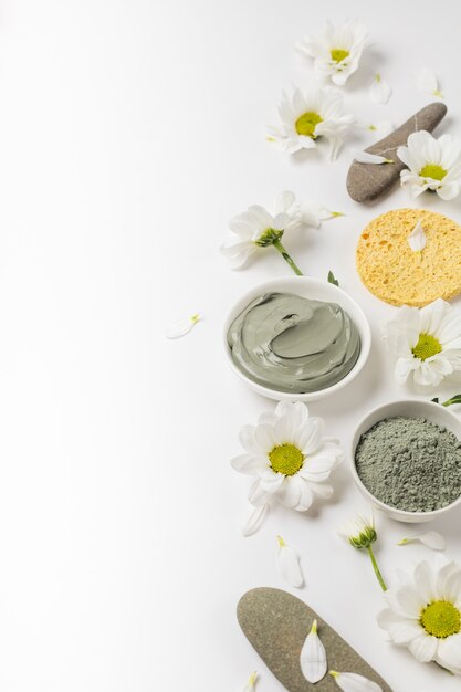 Masque d'argile naturel sec et humide avec des fleurs sur fond blanc