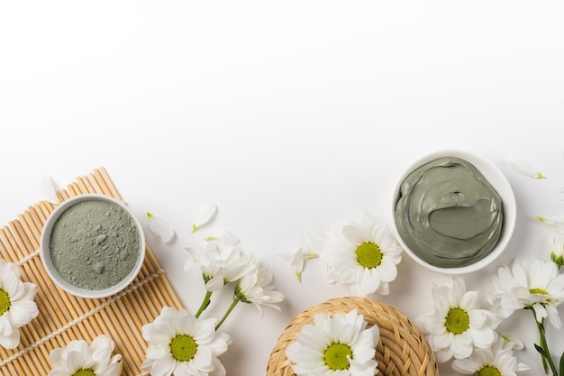 Masque d'argile naturel sec et humide avec des fleurs sur fond blanc