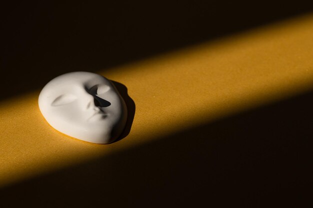 Masque blanc avec une expression faciale neutre avec des ombres sur fond d'or