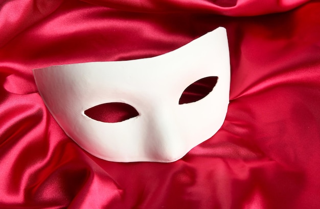 Masque blanc sur tissu de soie rouge