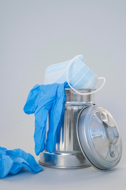 Photo masque bleu et gants médicaux en caoutchouc dans une poubelle sur fond gris gros plan pas de déchets organiques
