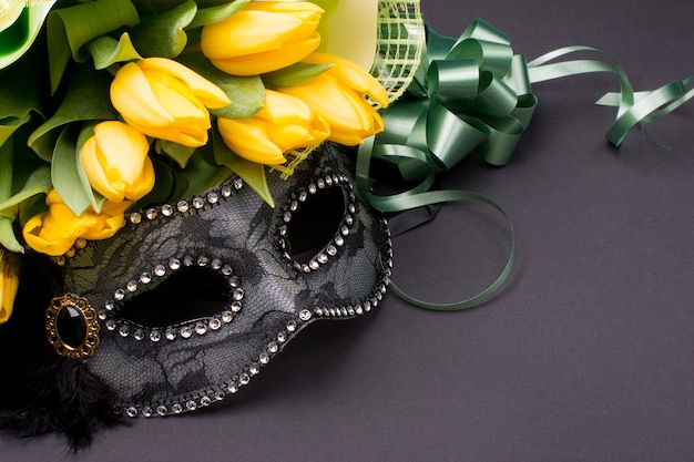 Masque de carnaval avec un bouquet de tulipes jaunes.