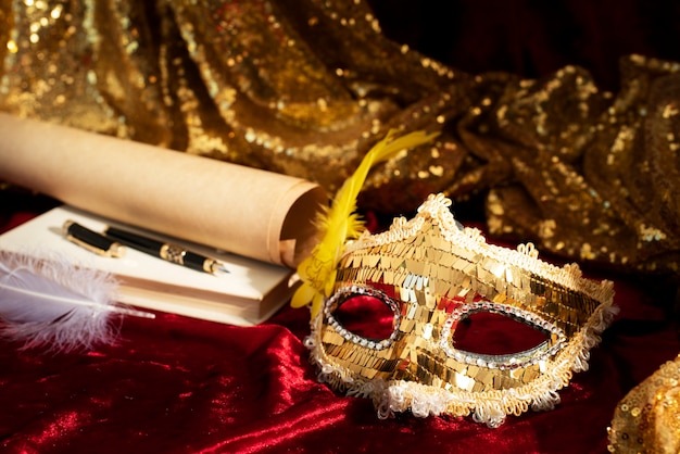 Photo masque de carnaval à côté d'un livre, d'un stylo et d'un papier