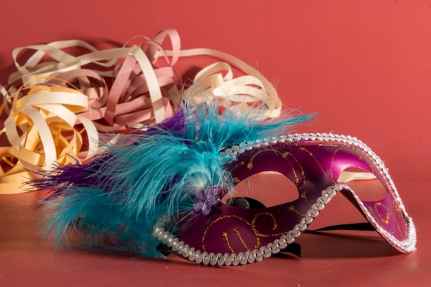 Masque de carnaval vénitien avec plumes et éléments typiques en arrière-plan