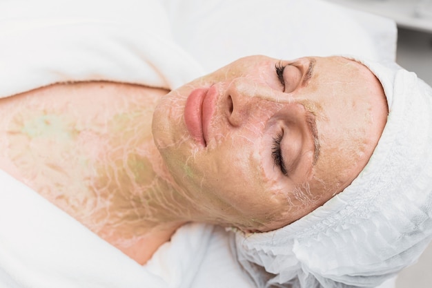 Masque enzymatique séché sur le visage et le cou d'une femme. Rajeunissement et lifting dans une clinique de cosmétologie