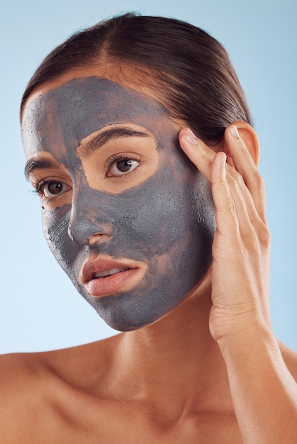 Masque facial au charbon de bois et beauté de la femme en tant que soin cosmétique ou soin du visage isolé sur fond de studio bleu Soins de la peau et jeune femme propre hydratation et crème dermatologique