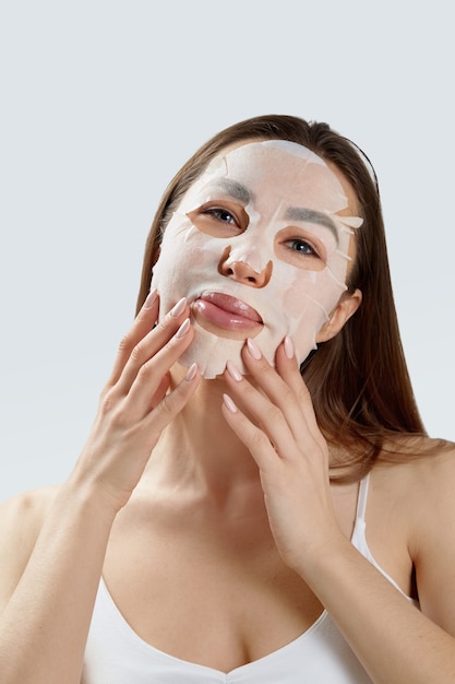 Masque facial de beauté. Belle jeune femme avec un masque hydratant en tissu sur le visage .Soin de la peau. Masque de spa cosmétique. Traitement facial