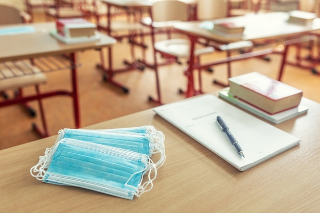 Masque facial sur un enseignant et un bureau d'école dans une salle de classe.