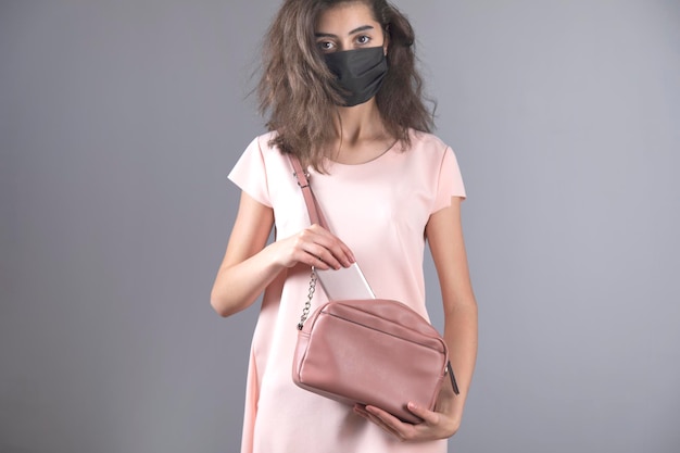 Masque facial femme et téléphone sur sac