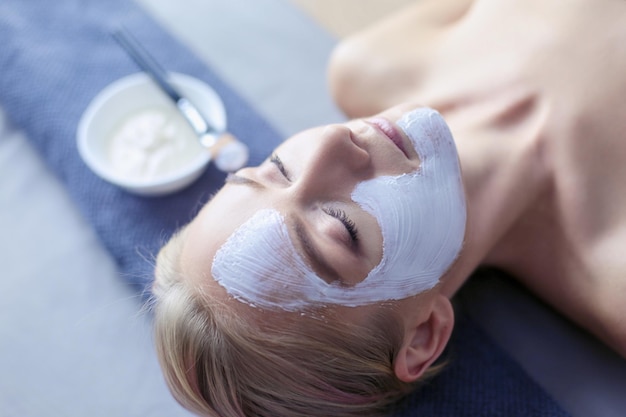 Masque facialbelle jeune fille au spa esthéticienne femme appliquant un masque facial