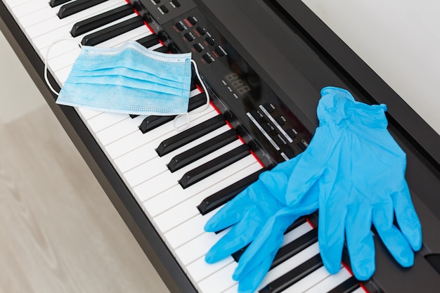 un masque et des gants de protection contre les virus se trouvent sur le piano