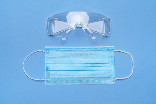 Masque et lunettes de sécurité pour protection individuelle sur fond bleu.