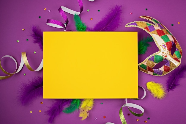 Masque de mardi gras ou de carnaval festif et coloré et accessoires sur un mur violet. Mise à plat, vue de dessus, espace copie