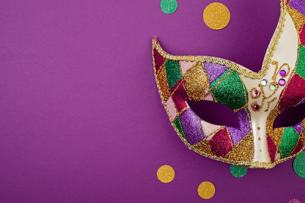 Masque de mardi gras ou de carnaval festif et coloré et accessoires sur un mur violet. Mise à plat, vue de dessus, espace copie