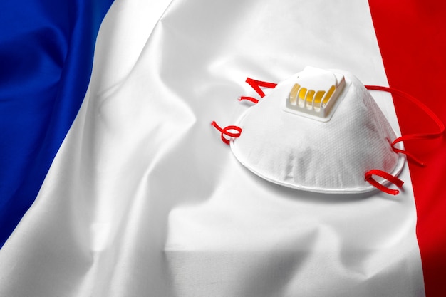 Masque médical sur le drapeau national de la France sur planche de bois