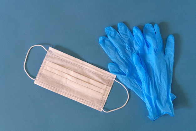 Masque médical et gants sur une surface bleue