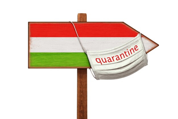 Un masque médical avec QUARANTAINE est suspendu à un pointeur de panneau avec l'image du drapeau de la Hongrie