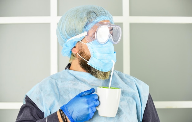 Masque médical en tant qu'homme de protection corona buvant du café dans un masque de protection respiratoire épidémie de pandémie de coronavirus Médecin respirant un masque respiratoire L'hôpital ou la pollution protègent le masquage du visage