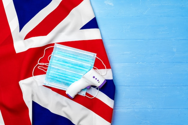 Masque médical et thermomètre sans contact sur drapeau britannique