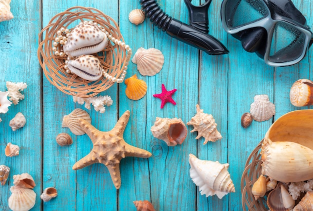 Photo masque de plongée avec étoile de mer et coquillages sur vieux bois bleu. vue de dessus. lay plat.