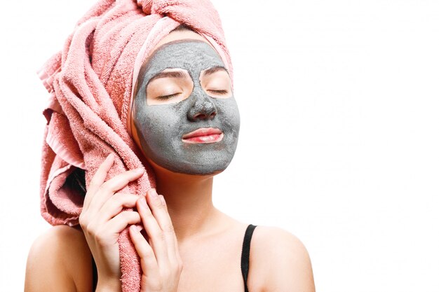 masque pour femme peau, fille heureuse tenant une serviette, femme jouit d'un masque pour la peau du visage, photo isolée, yeux fermés avec plaisir