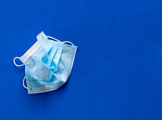 Masque De Protection Médical Froissé Contre Le Coronovirus Sur Une Surface Bleue.