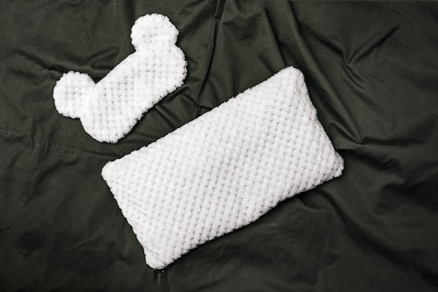 Masque de sommeil en forme d'animal et coussin moelleux pour un confort de repos la nuit sur fond textile gris. Vue de dessus. Mise à plat.