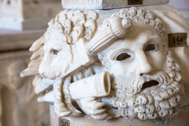 Masque de théâtre antique, fait de marbre, situé à la base d'une colonne romaine à Rome - Italie