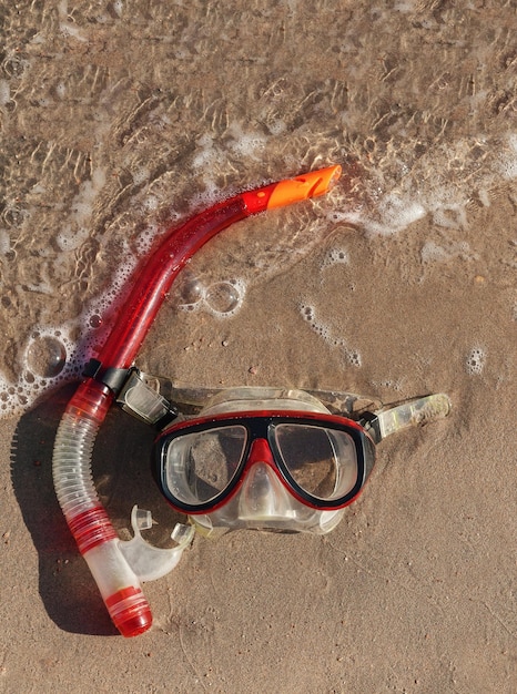 Masque et tuba allongé sur du sable humide avec des vagues