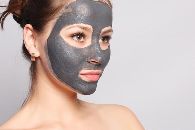 Masque de visage de femme. Portrait de belle fille enlevant le masque de peeling noir cosmétique de la peau du visage. Gros plan d'une jeune femme séduisante avec un maquillage naturel et un masque cosmétique sur le visage. Haute résolution