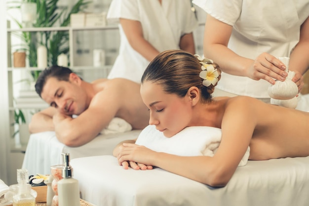 Massage au corps avec des boules d'herbes chaudes dans un spa de jour tranquille