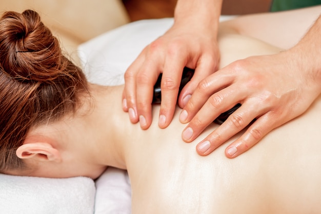 Massage aux pierres sur le dos de la femme